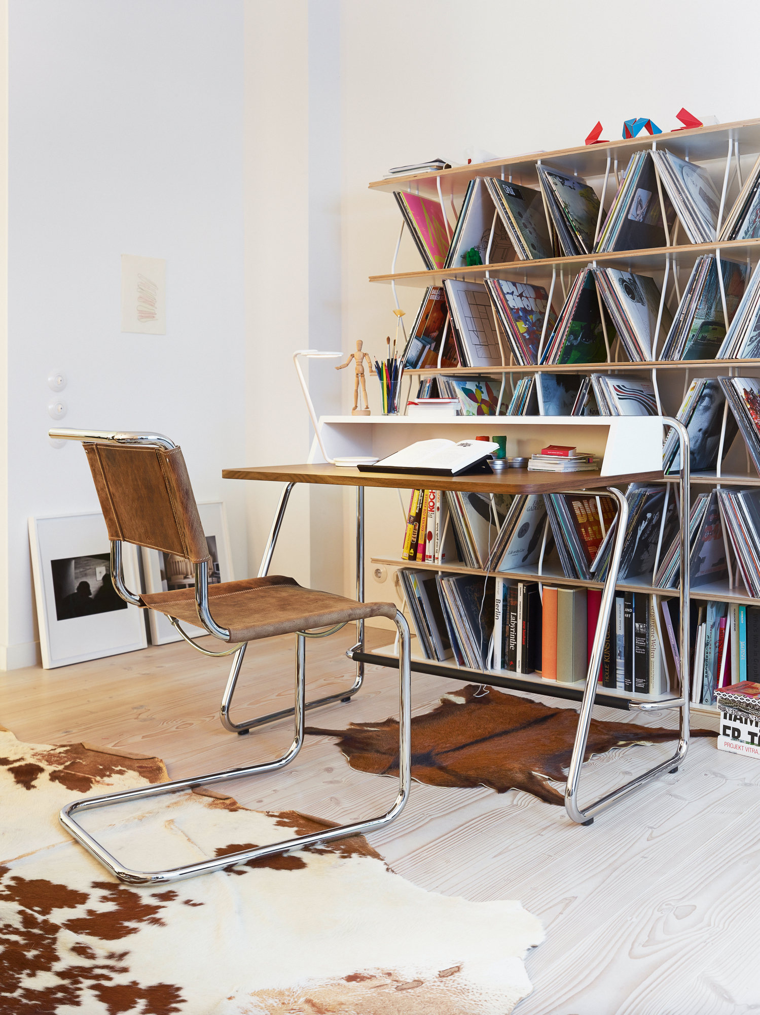 S 1200 Thonet Sekretär mit Stahlrohrgestell und passendem Ledersessel vor Bücherregal.