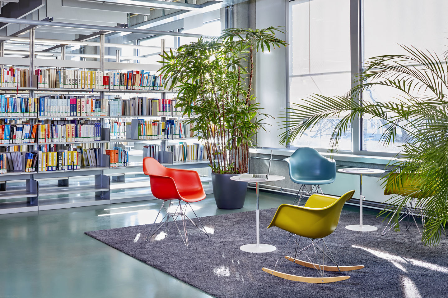 Eames Schaukelstuhl RAR von Vitra in Gelb, Rot und Blau in einer Bibliothek.