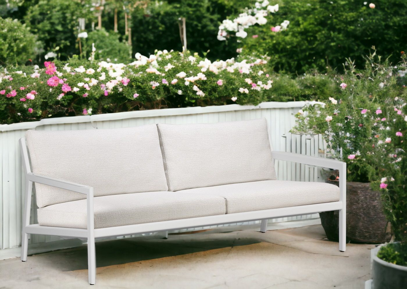 Jack Outdoor Sofa mit weißem Aluminiumrahmen und hellen Polstern im Garten.