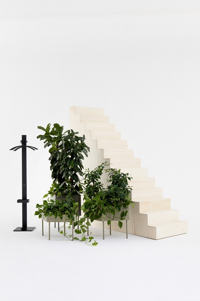 Schwarzer Standfree P Garderobenständer mit Schirmständer von Cascando neben Treppe und Pflanzen. Moderner Garderobenständer für Büro und Zuhause.