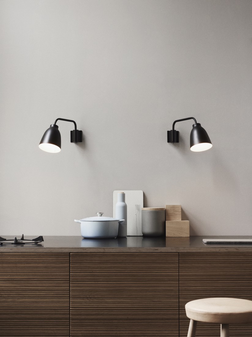 Zwei schwarze Caravaggio Wandleuchten von Fritz Hansen über einer Küchenzeile.