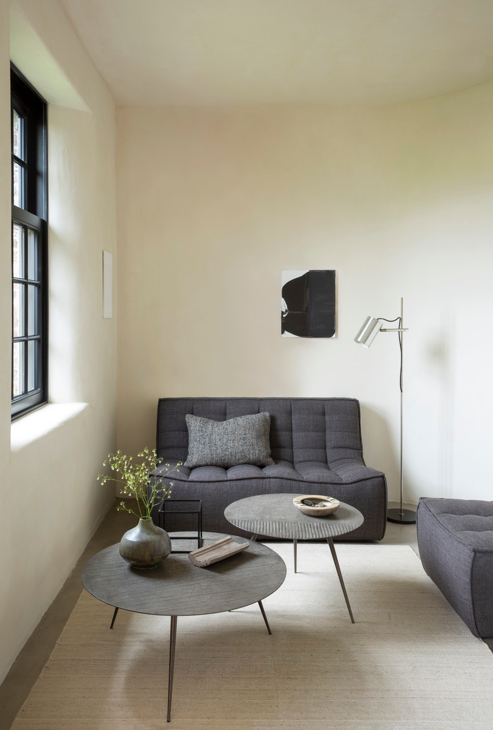 Wohnzimmer mit Ethnicraft Luna Couchtisch in Lava und grauem Sofa.