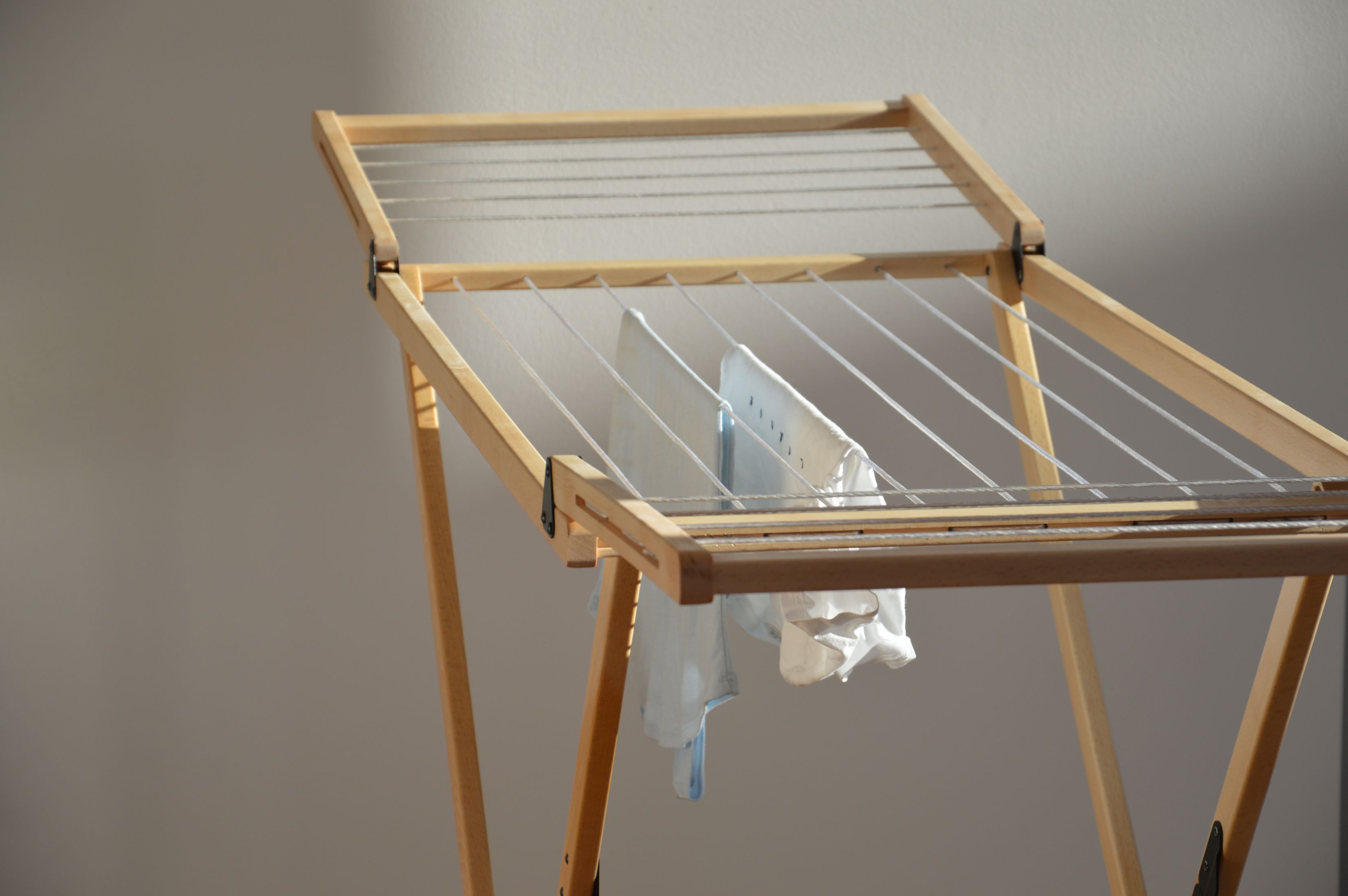 Vivo Wäscheständer Jan Kurtz aus Holz mit aufgehängter, weißer Wäsche vor hellem Hintergrund.