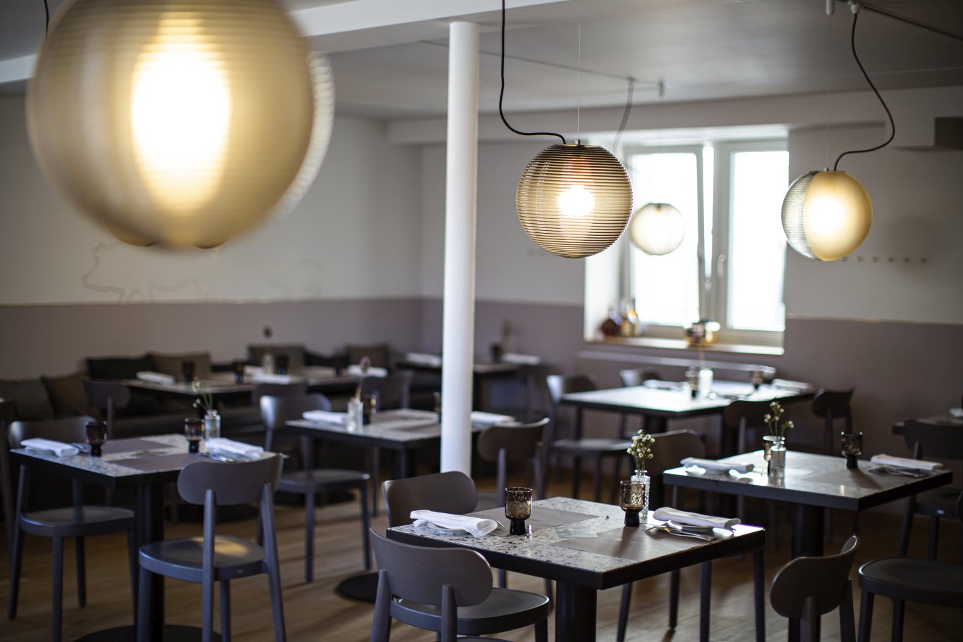 Innenaufnahme eines Restaurants mit mehreren Stellar Pendelleuchten von Pulpo in Rauchgrau. Moderne Beleuchtung.