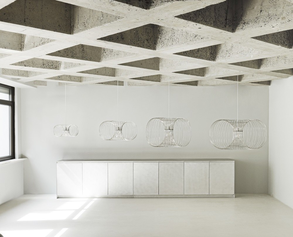 Coil Lampe von Normann Copenhagen: Vier moderne Pendelleuchten in verschiedenen Größen über einem Sideboard.