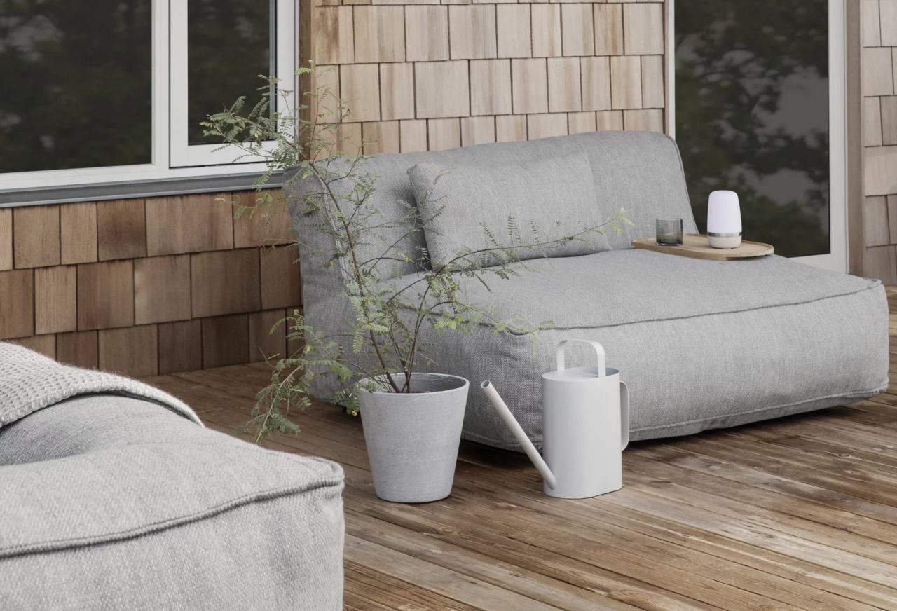 Blomus Grow Kissen Coal Outdoor: Graues Loungekissen mit Pflanze und Gießkanne auf Holzterrasse.