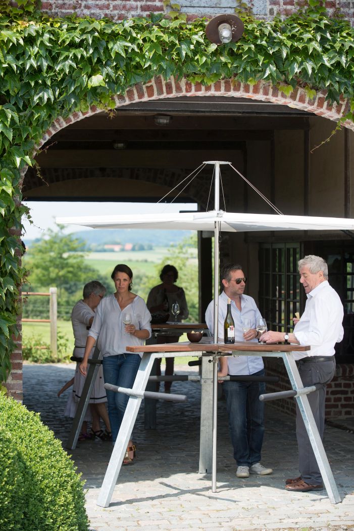 Inumbrina Sonnenschirm: Menschen genießen Wein unter einem modernen, quadratischen Sonnenschirm im Freien.