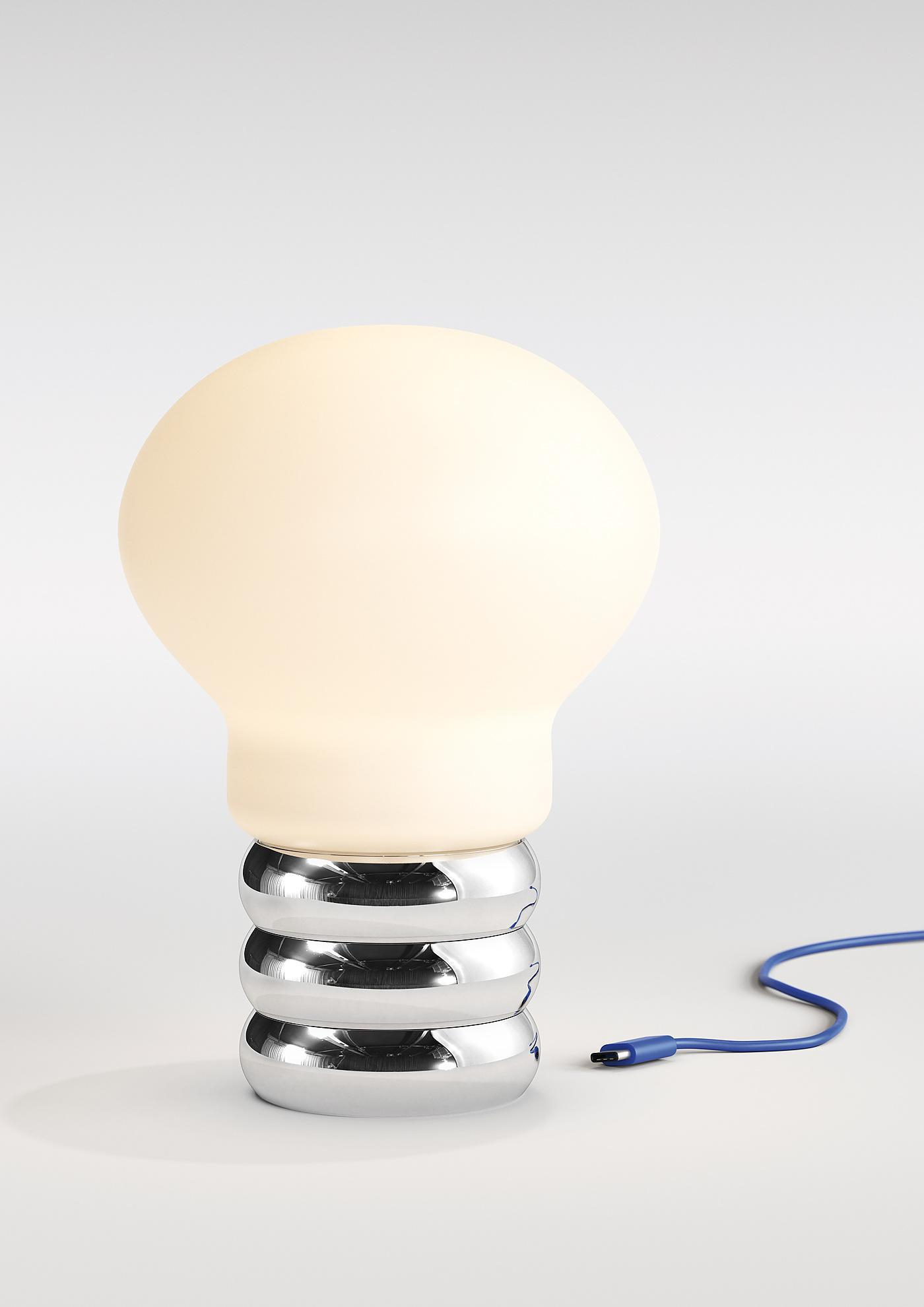 b.bulb Akkuleuchte: Moderne Tischleuchte im Glühbirnen-Design mit Chromfuß und blauem USB-Kabel.
