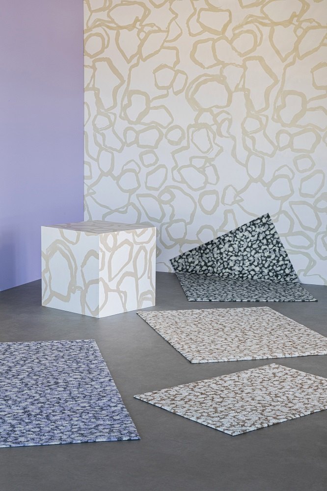 Mehrere Heymat Fußmatten mit Sandstein-Muster in verschiedenen Farben auf grauem Boden. Indoor Fußmatte für den Eingangsbereich.