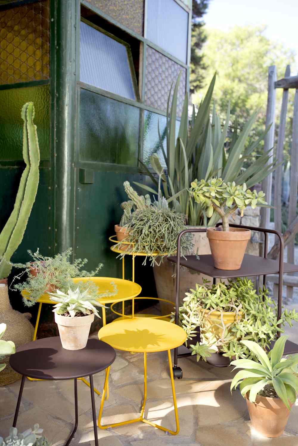 Gelbe und braune Cocotte Beistelltische von Fermob im Außenbereich mit Pflanzen und Dekoration.