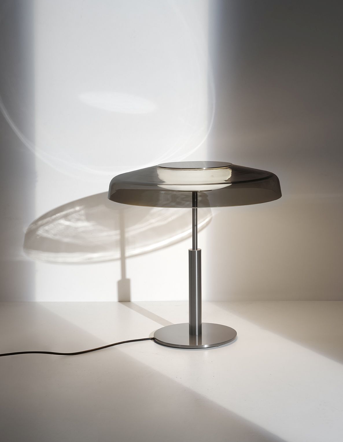 Dora Tischleuchte von Oluce: Moderne Lampe mit grauem Schirm und silbernem Fuß.