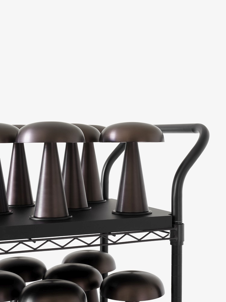 Mehrere Como SC53 Akkuleuchten auf einem Regal, moderne Tischleuchten in Bronze.