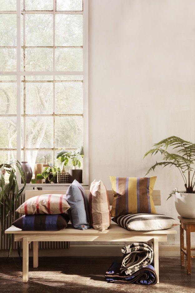 Peka Bank von Ferm Living mit gestreiften Kissen und Decken in einem hellen Raum.