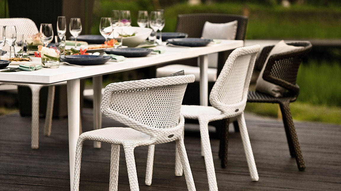 Nahaufnahme des weißen Dedon Seashell Armlehnstuhls am Esstisch im Freien.