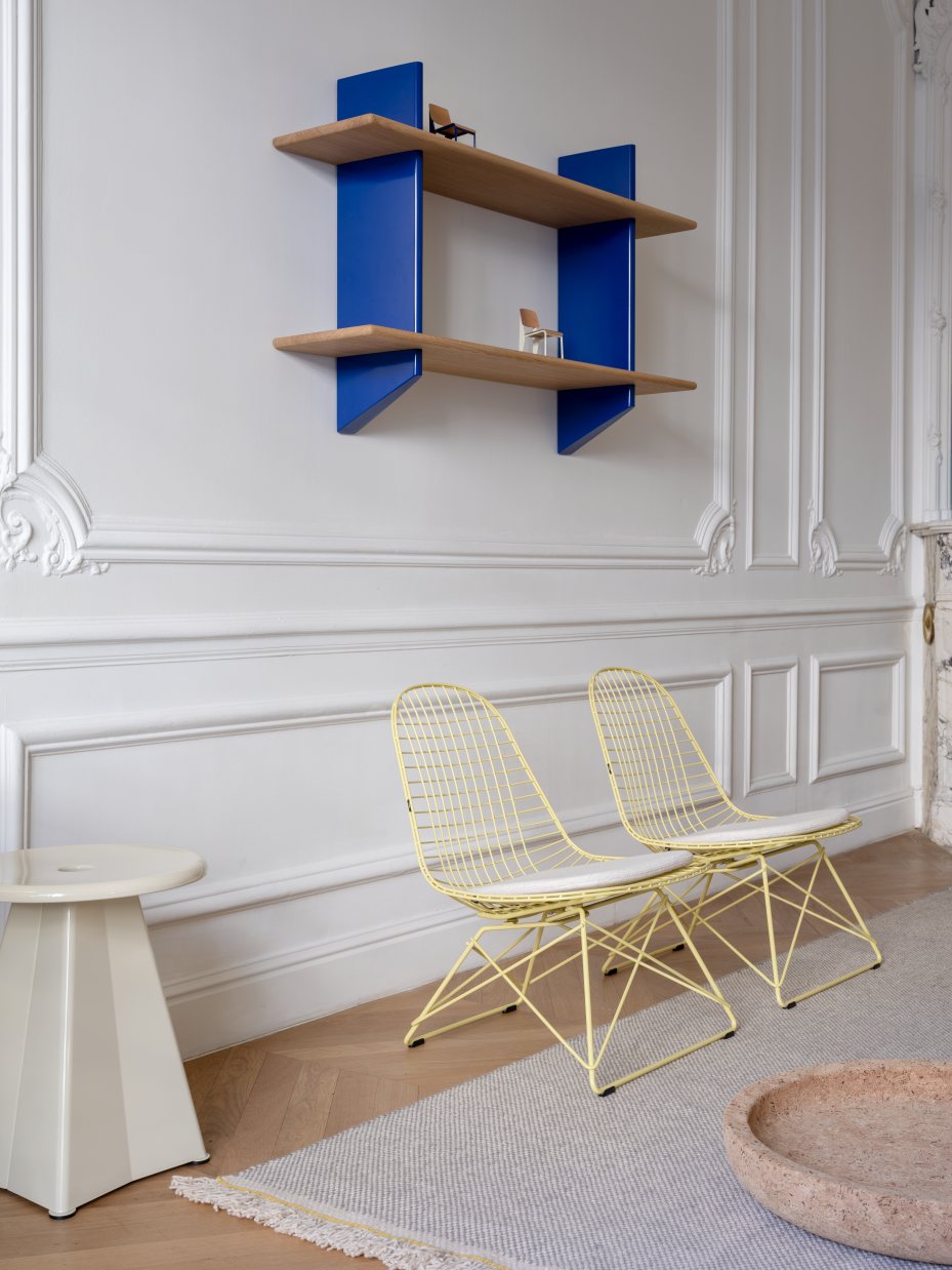 Beiger Tabouret Métallique Hocker von Vitra neben gelben Drahtstühlen in stilvollem Interieur.