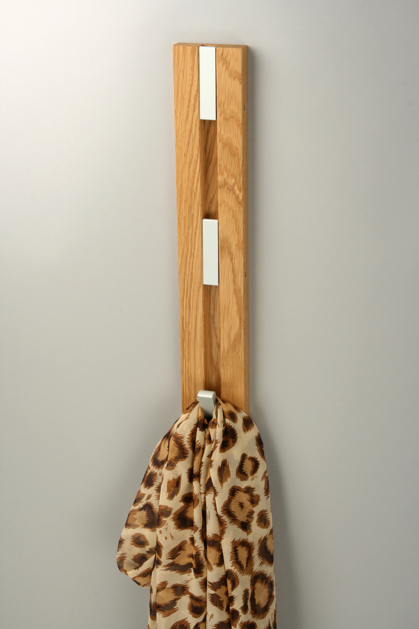Knax Wandgarderobe mit vier Haken aus Holz, vertikal an der Wand montiert, mit Schal.