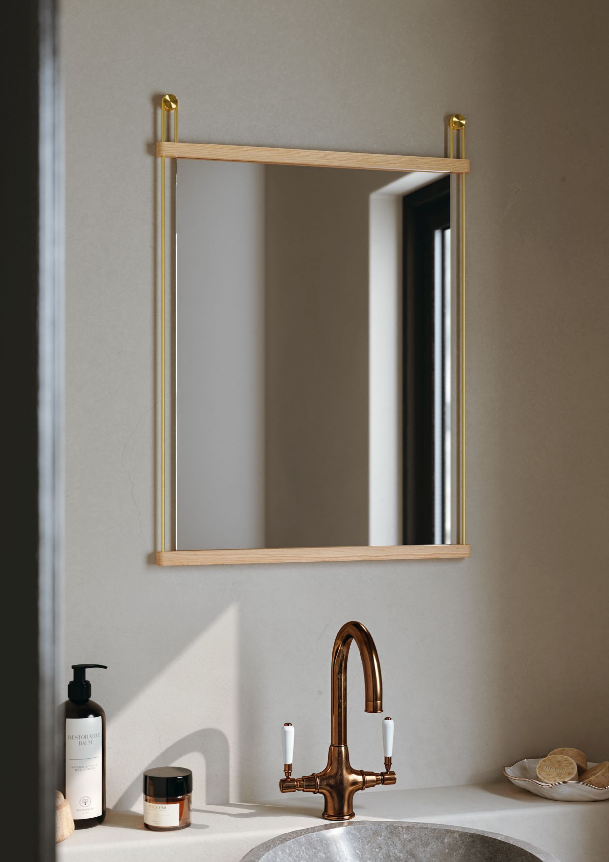 Quadratischer Suspended Mirror Small von Woud mit hellem Holzrahmen und goldenen Aufhängungen im Badezimmer.