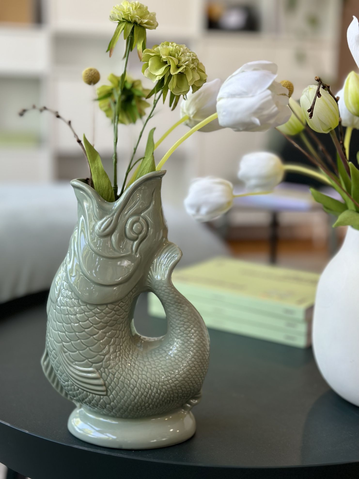 Nahaufnahme der Gluckigluck Karaffe in Salbeigrün XL, gefüllt mit Blumen, als dekorative Vase.