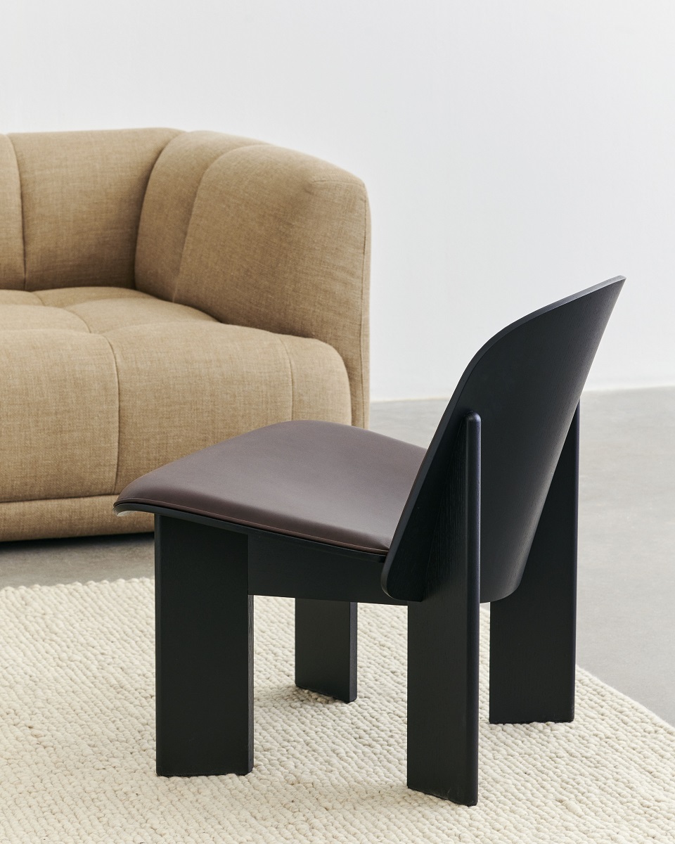 Nahaufnahme des Peas Random Teppichs in Hay-Farbe mit modernem Stuhl und Sofa.