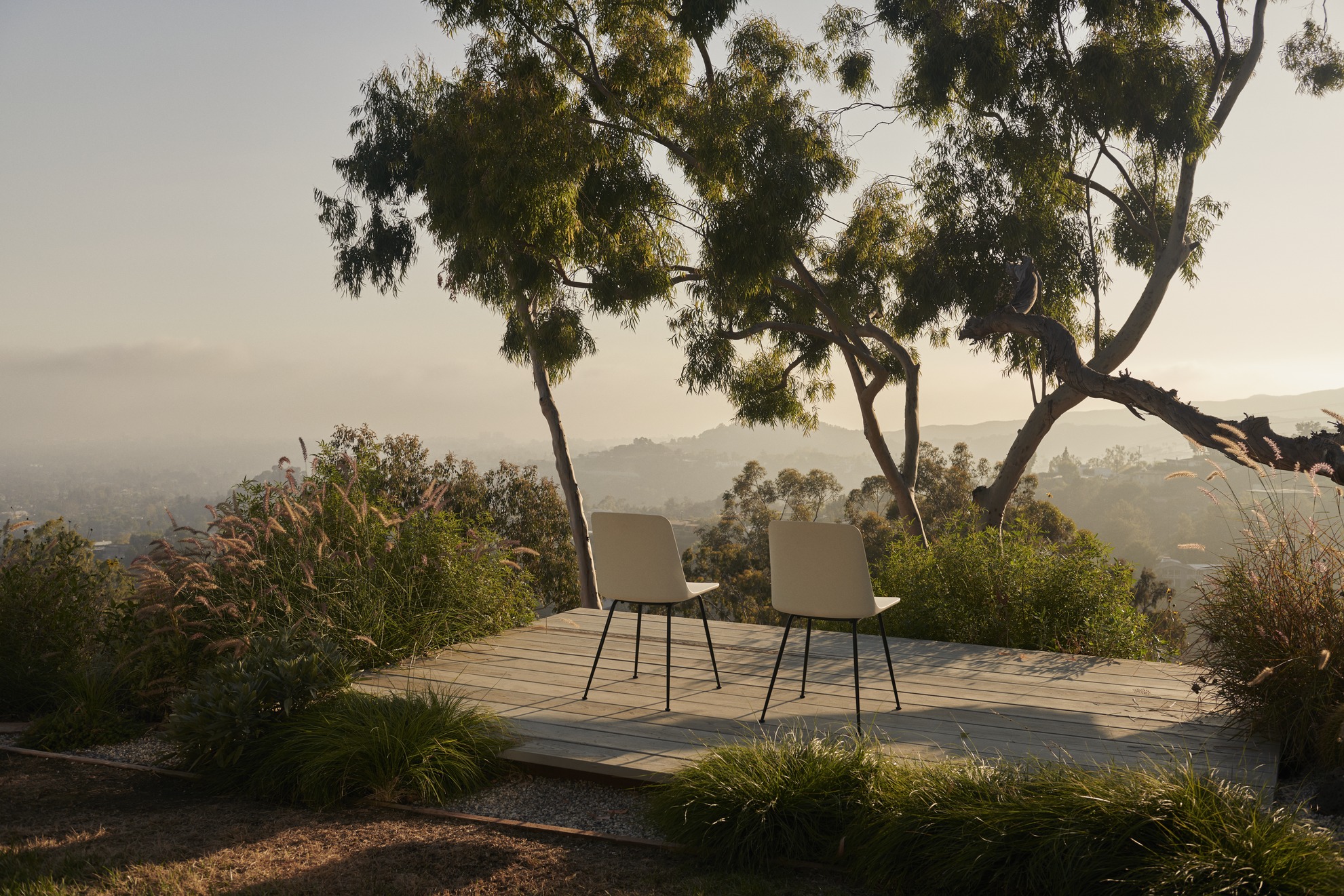 Zwei Rely HW70 Outdoor Stühle von AndTradition auf einer Holzterrasse mit Ausblick.