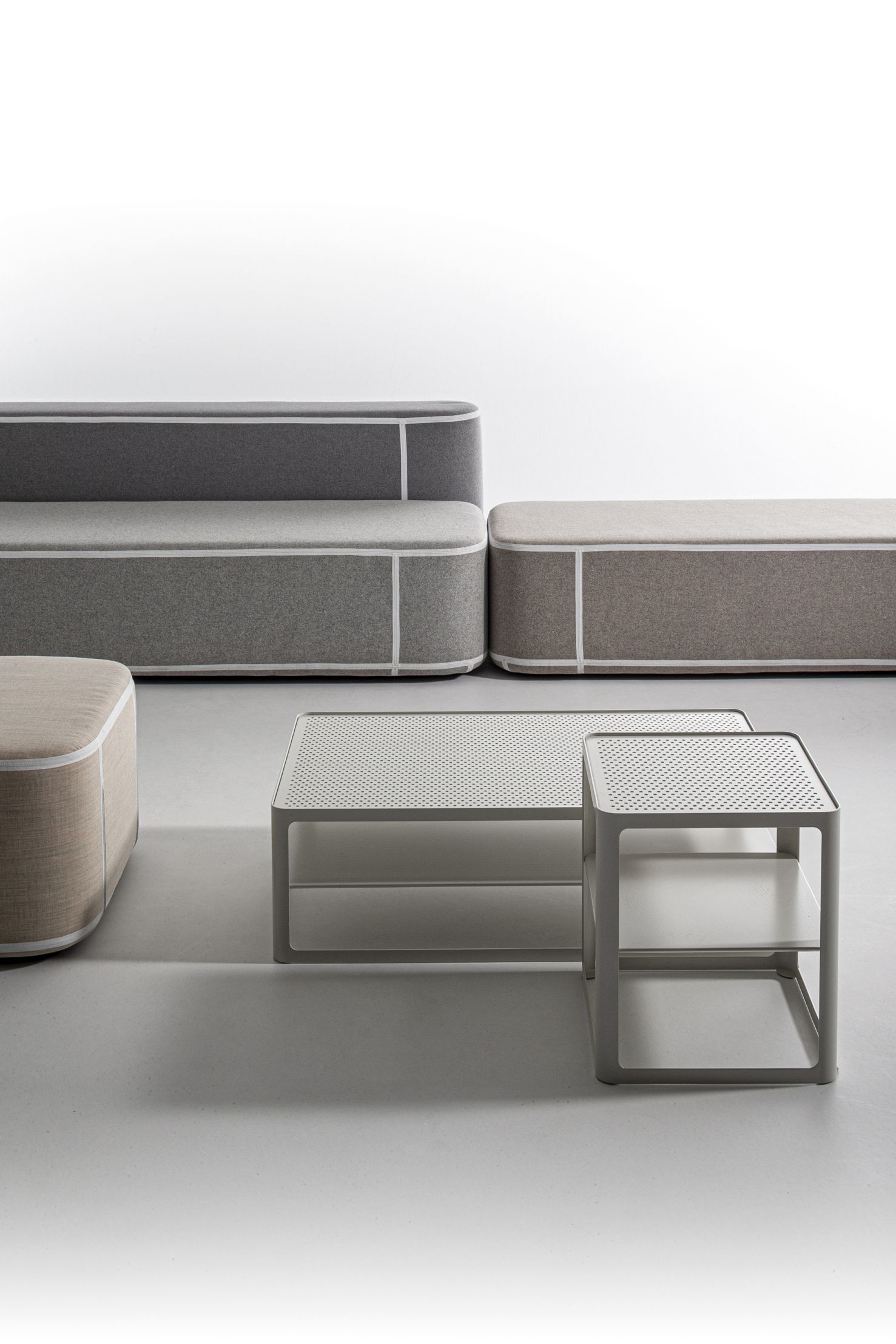 Tape Sofatisch von Moroso und modulare Sofas in Grau- und Beigetönen mit weißer Akzentuierung.