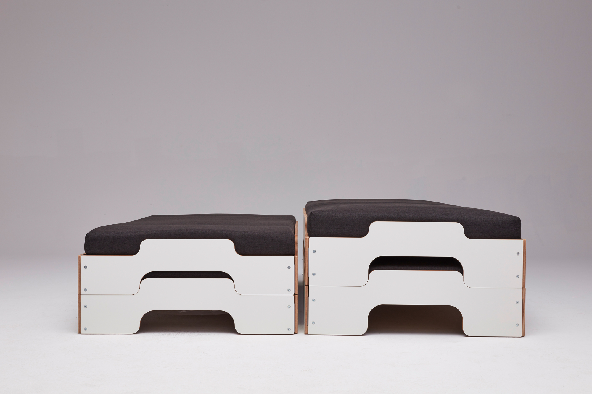 Zwei gestapelte Liegen von Müller Möbelwerkstätten mit grauen Auflagen und weißen Rahmen.