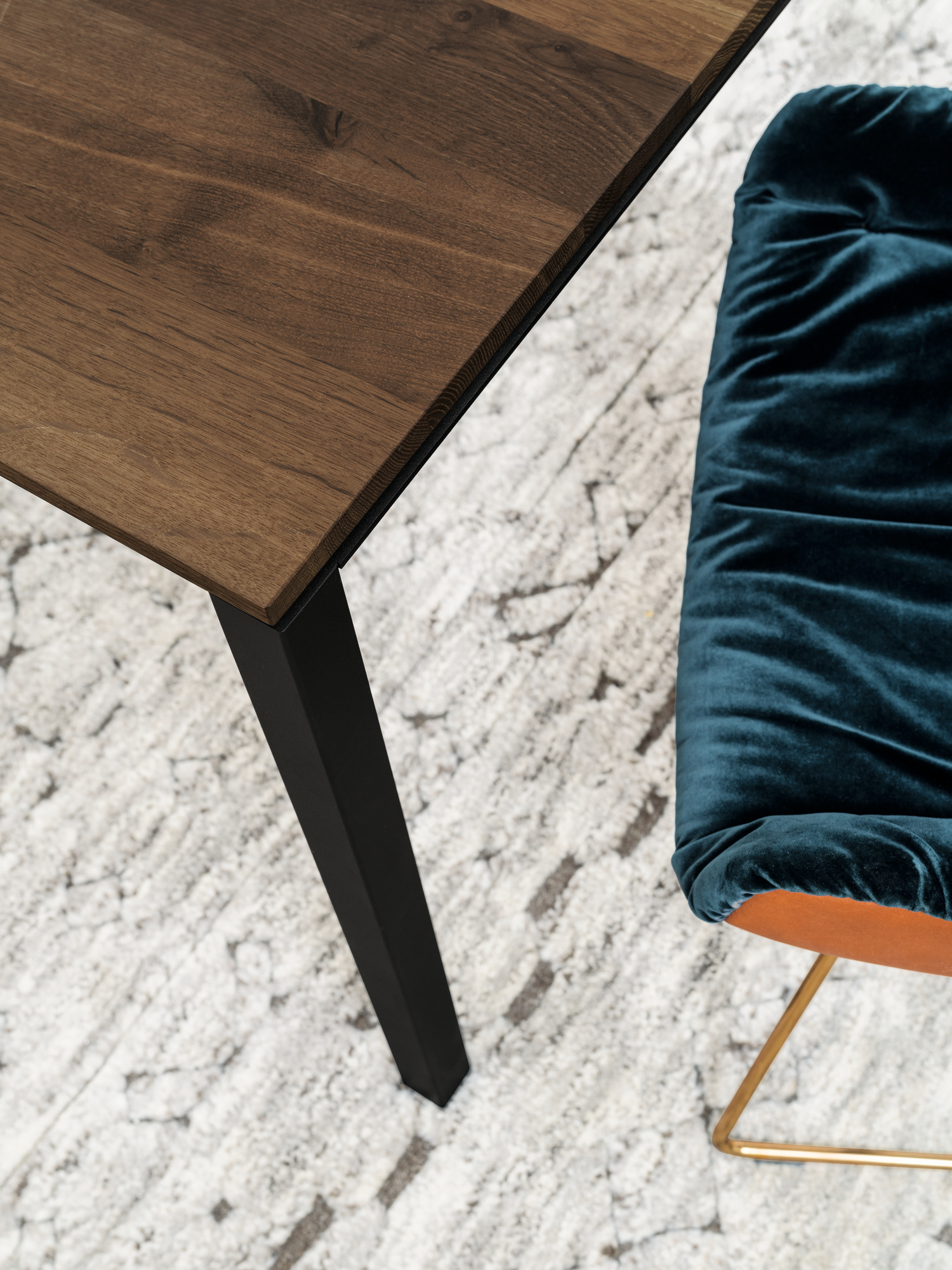 Detailaufnahme des Janua S 600 Tisches mit geräucherter Eichenplatte und schwarzem Metallgestell.