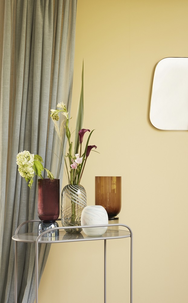 Verschiedene dekorative Vasen, darunter eine grün-weiße Glasvase von Hübsch Interior, mit Blumen auf einem Beistelltisch.