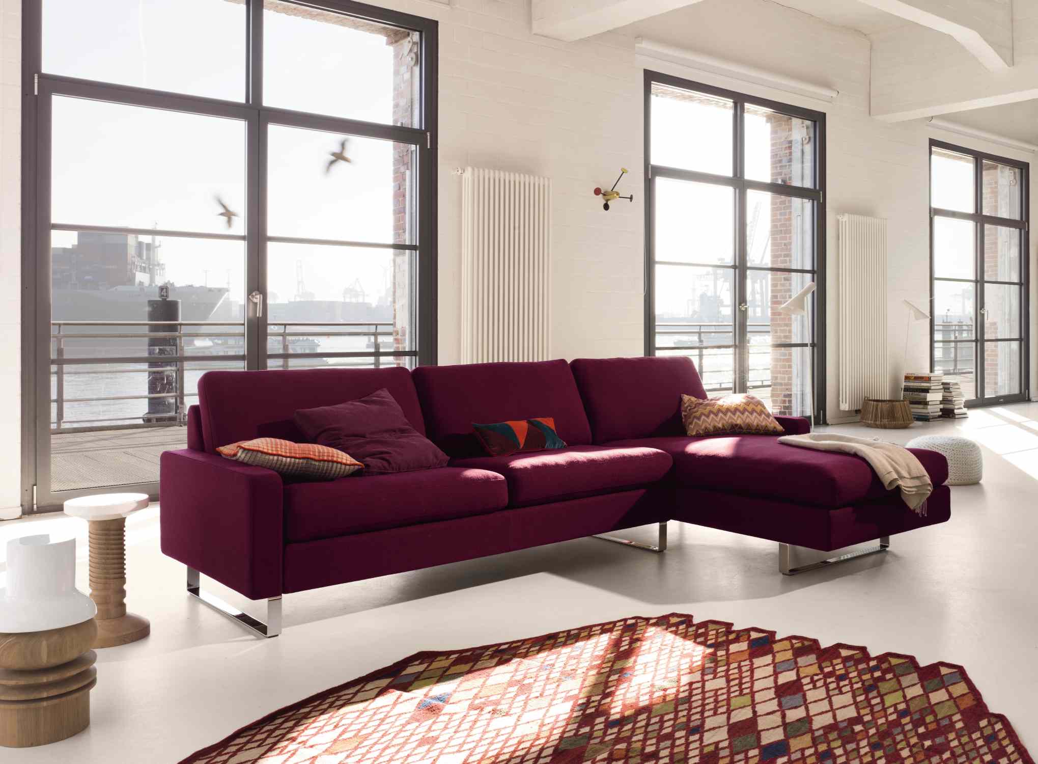 Conseta Sofa von Cor in Lila mit Kissen und Metallfüßen in modernem Wohnzimmer.