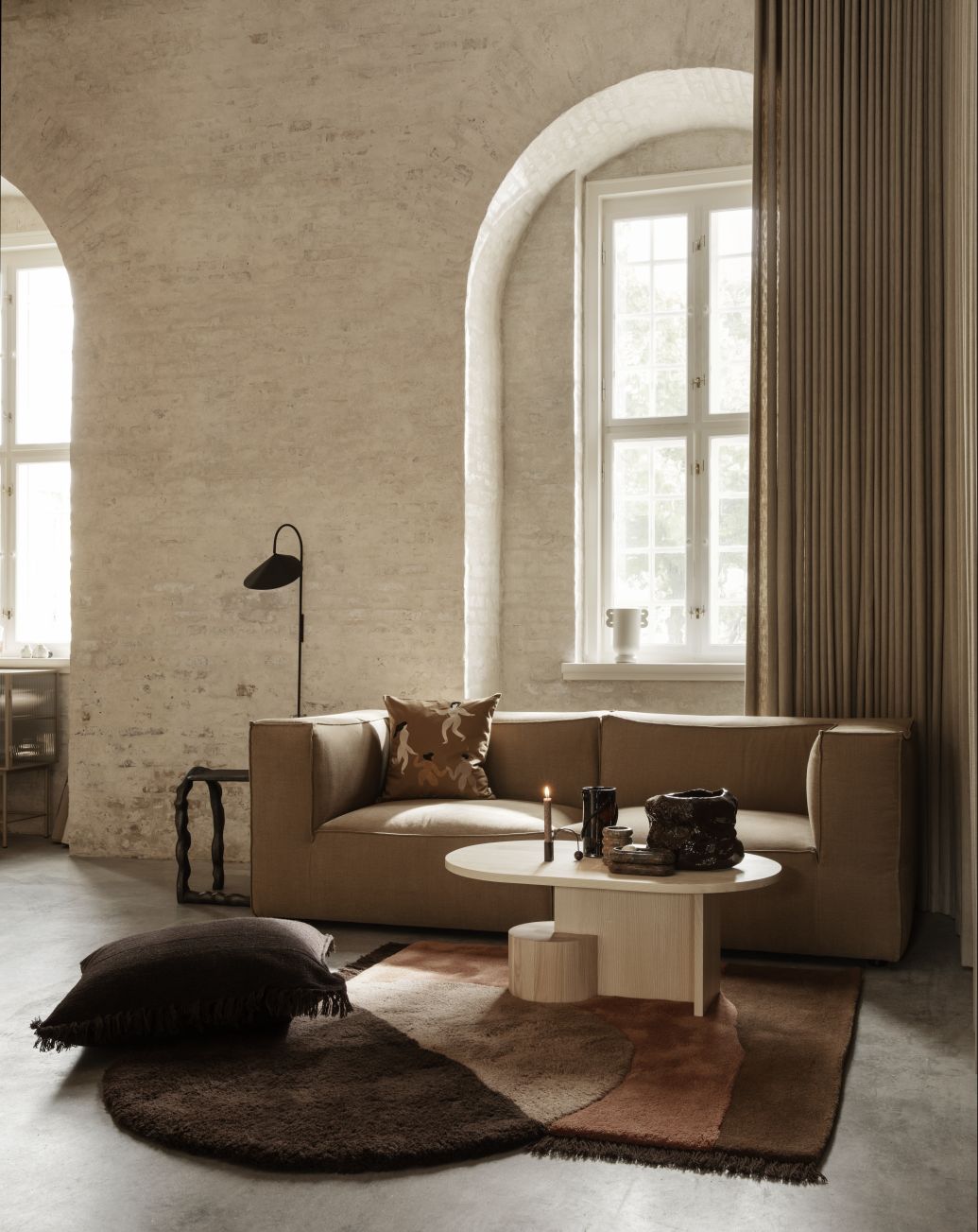 Wohnzimmer-Szene mit Ferm Living Insert Couchtisch aus Esche, schwarz gebeizt, auf einem gemusterten Teppich.