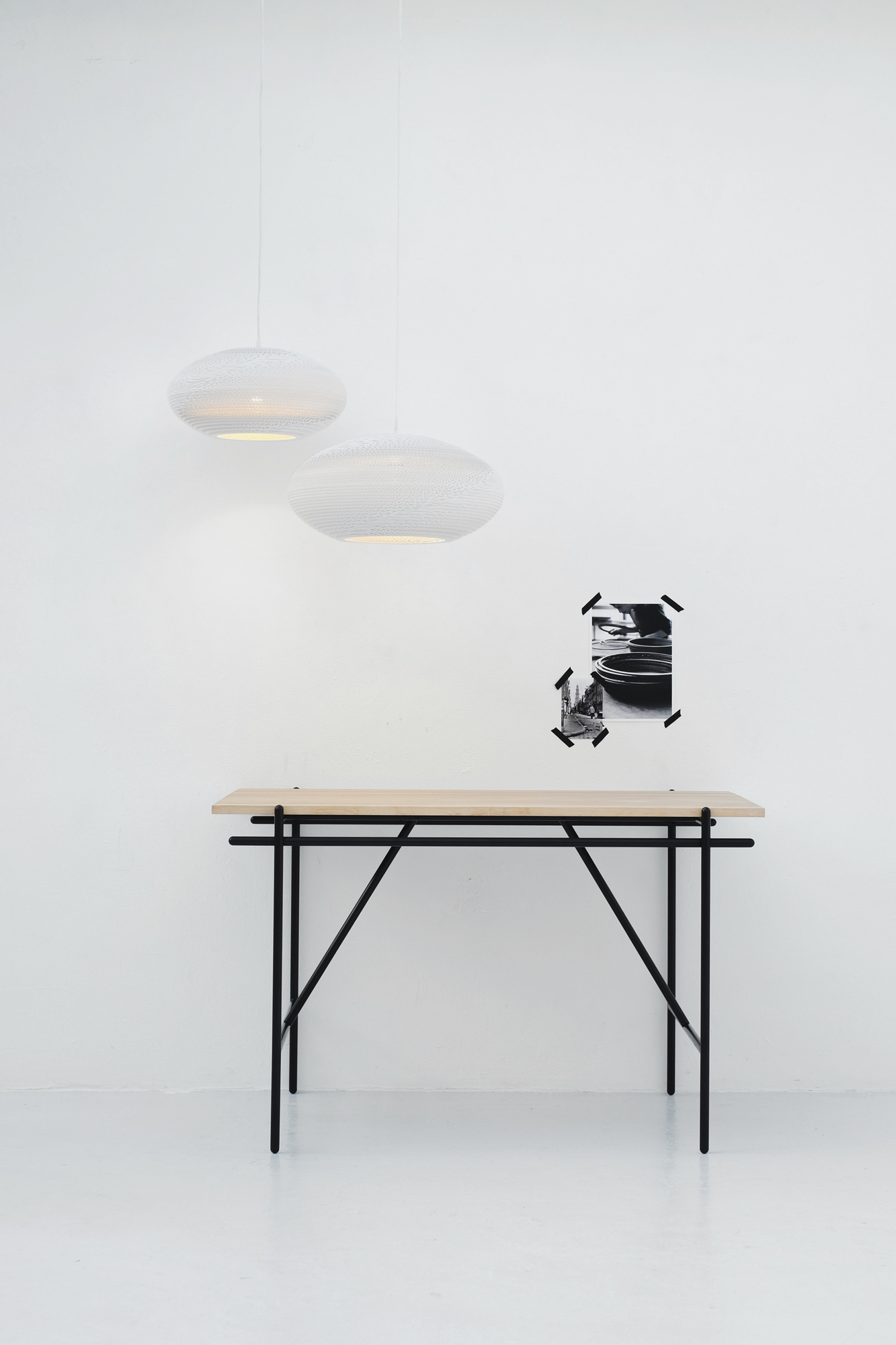 Zwei weiße Scraplights Disc Hängeleuchten von Graypants über einem Tisch mit schwarzem Gestell.