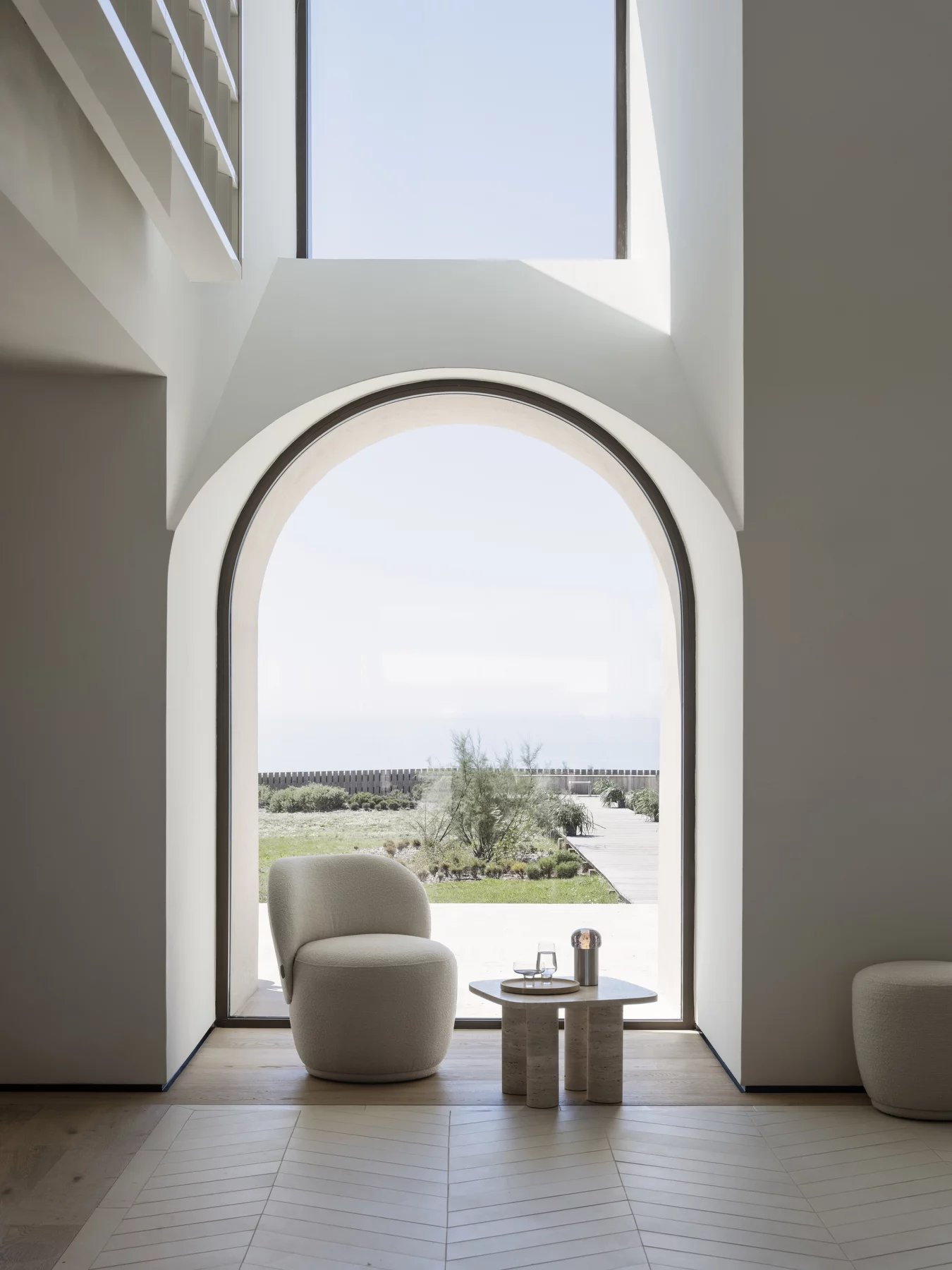 Blomus Volos Beistelltisch aus Travertin in modernem Wohnzimmer mit Sessel und großem Fenster.