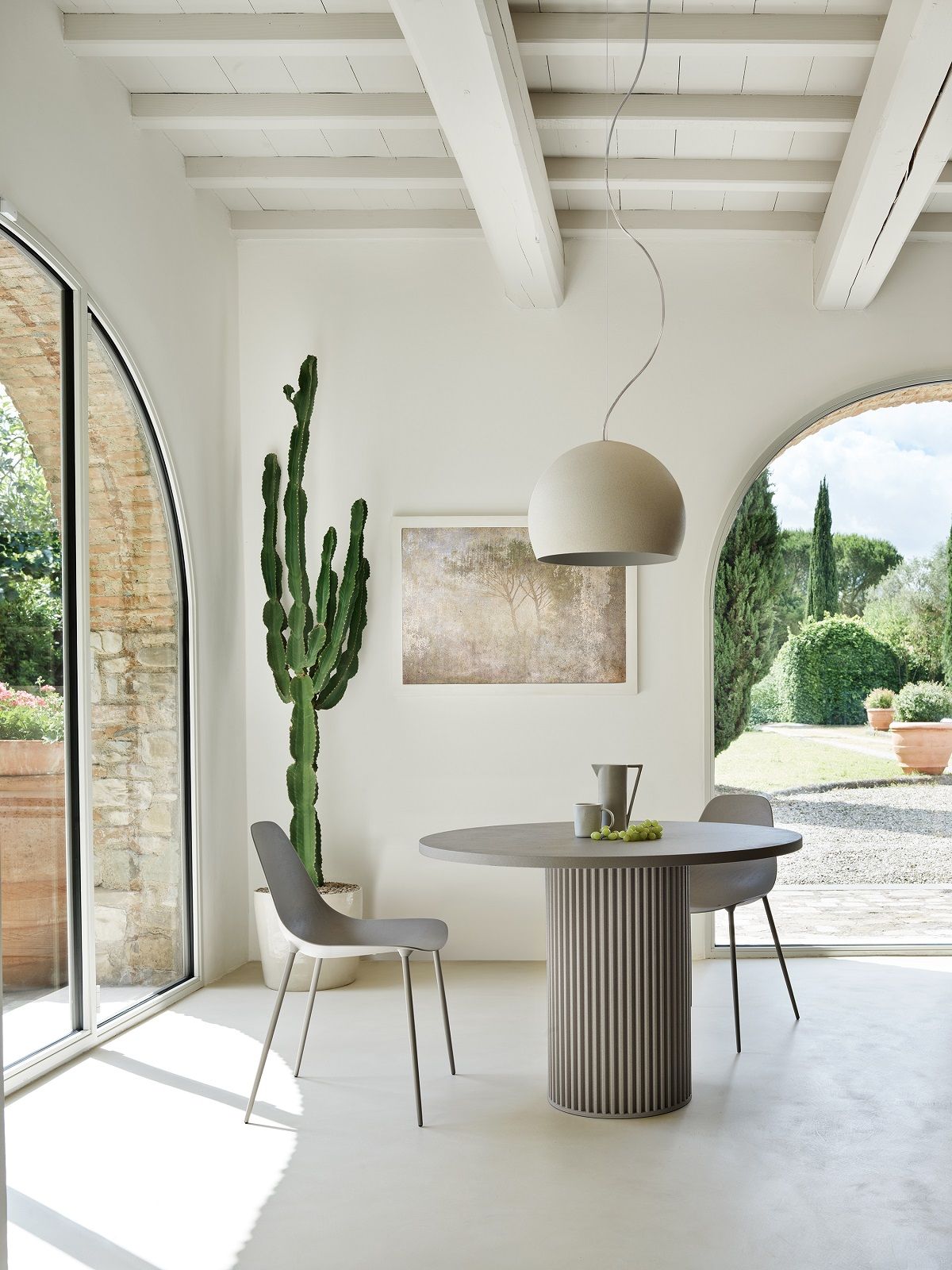 Heller Raum mit rundem Hercle Table Tisch und zwei Stühlen, geeignet für Indoor und Outdoor.