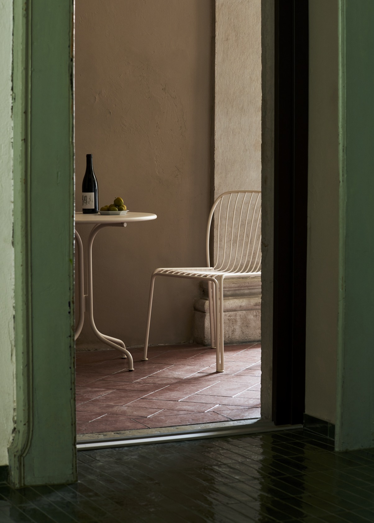 AndTradition Thorvald SC96 Outdoor Tisch mit Stuhl, Flasche Wein und Obst auf Terrasse.