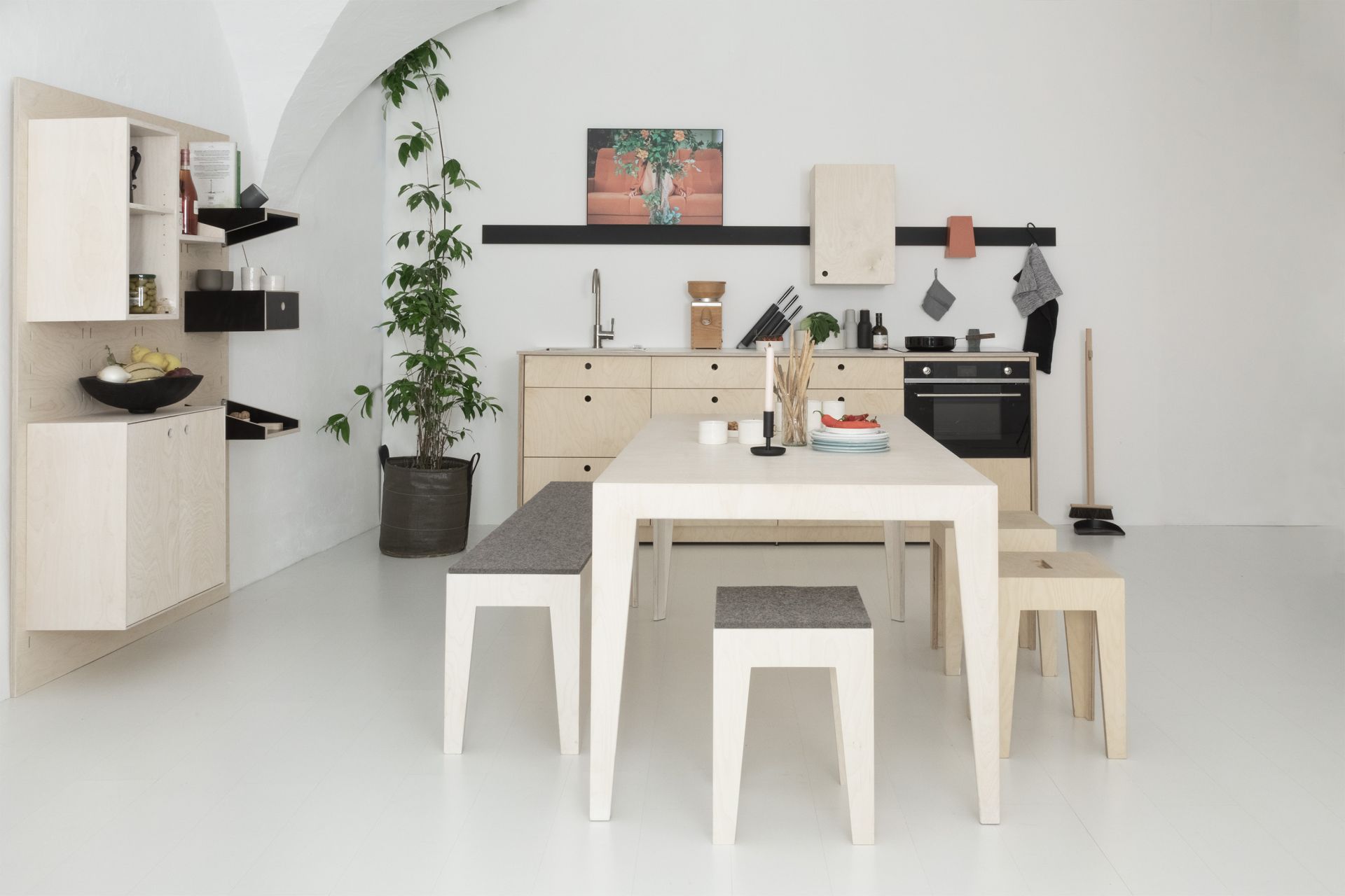 Helle Küche mit Esstisch und Bänken aus hellem Holz, Küchenschränken und Dekorationen im minimalistischen Stil.