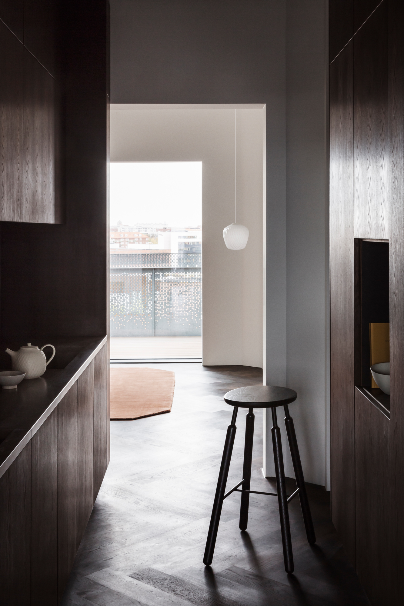 Moderne Küche mit AndTradition Blown Pendelleuchte, die über einem Hocker in minimalistischem Interieur hängt.