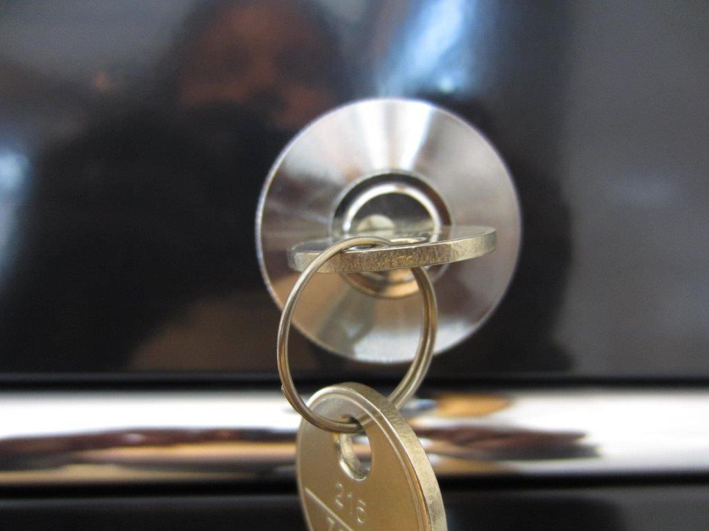Nahaufnahme eines USM Haller Möbelschlosses mit Schlüssel als Ersatzteil für modulare Möbel.