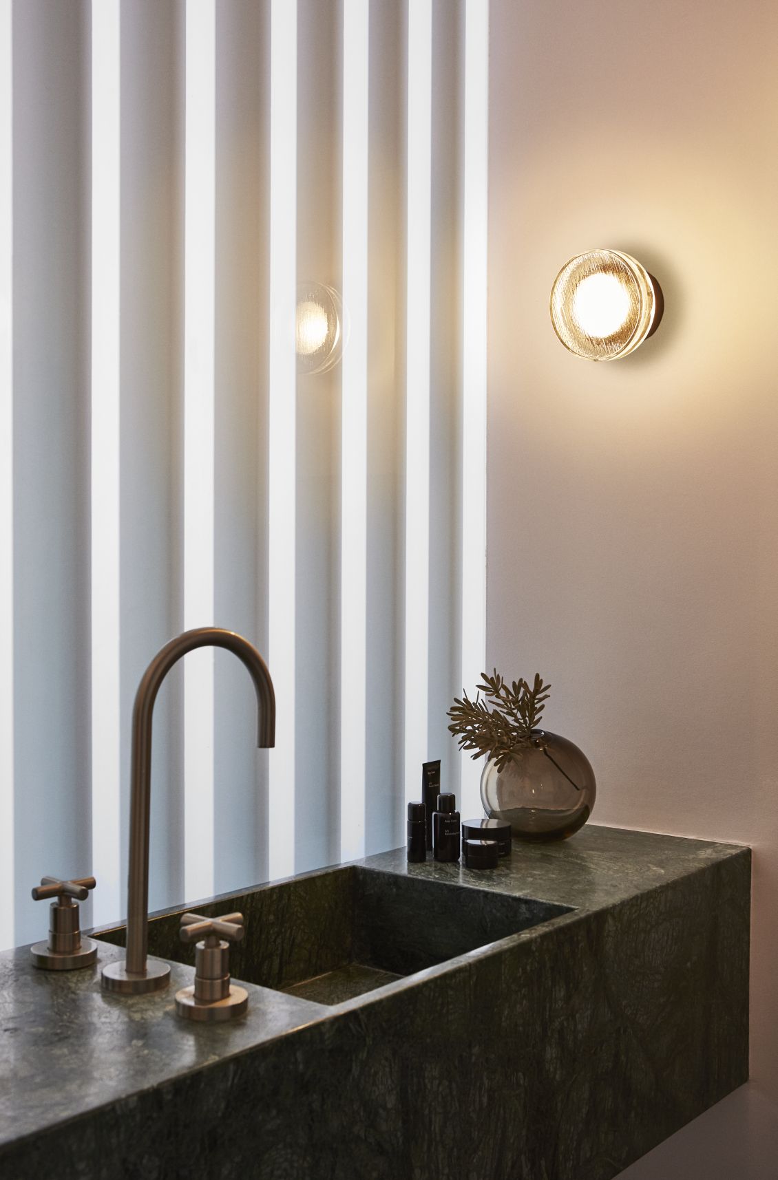 Badezimmer mit Marmorwaschbecken und zwei Roc Wandleuchten von Marset für stimmungsvolle Beleuchtung.