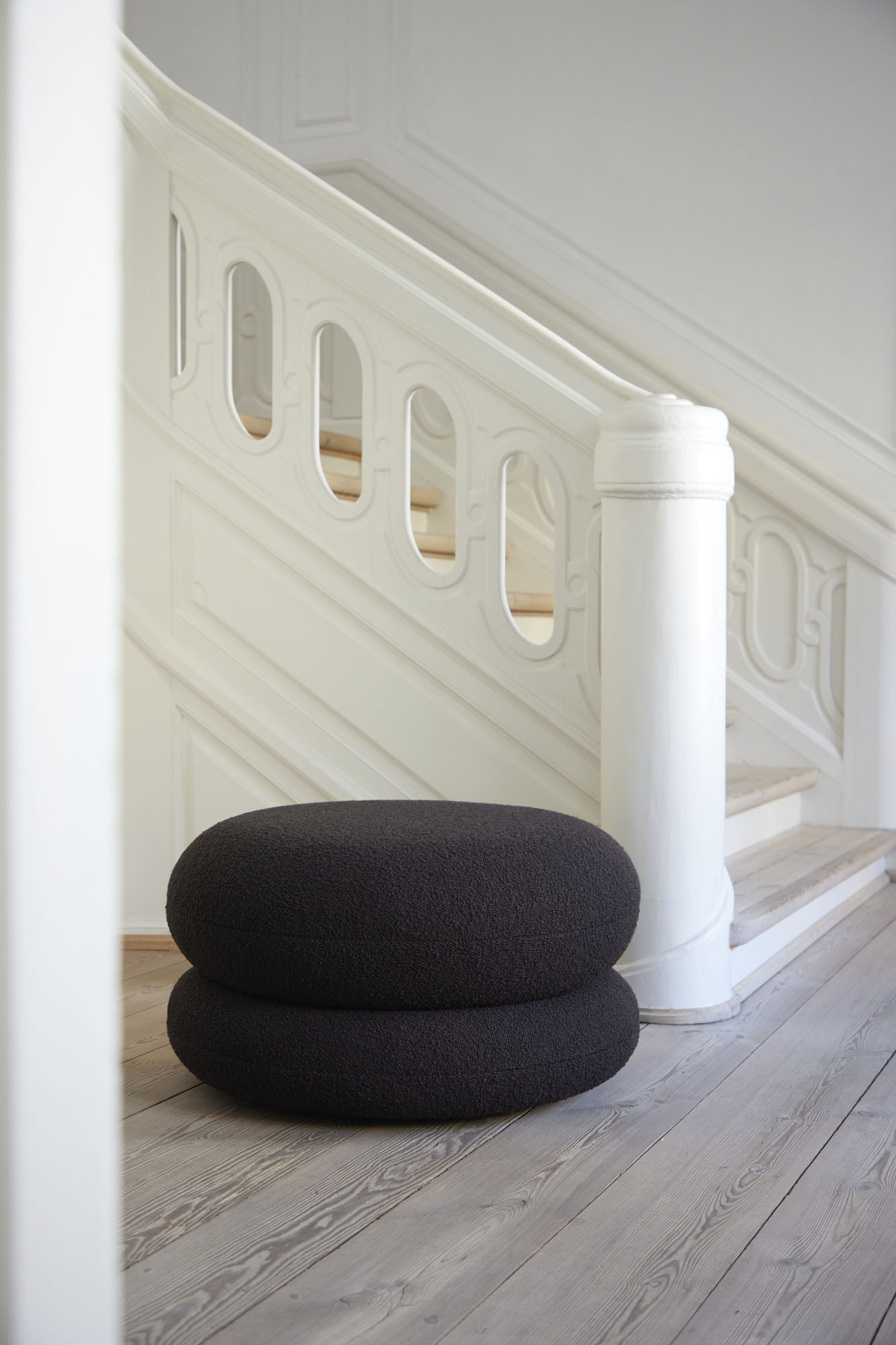 Schwarzer Easy Pouf Hocker von Verpan vor einer weißen Treppe, moderner Sitzhocker.