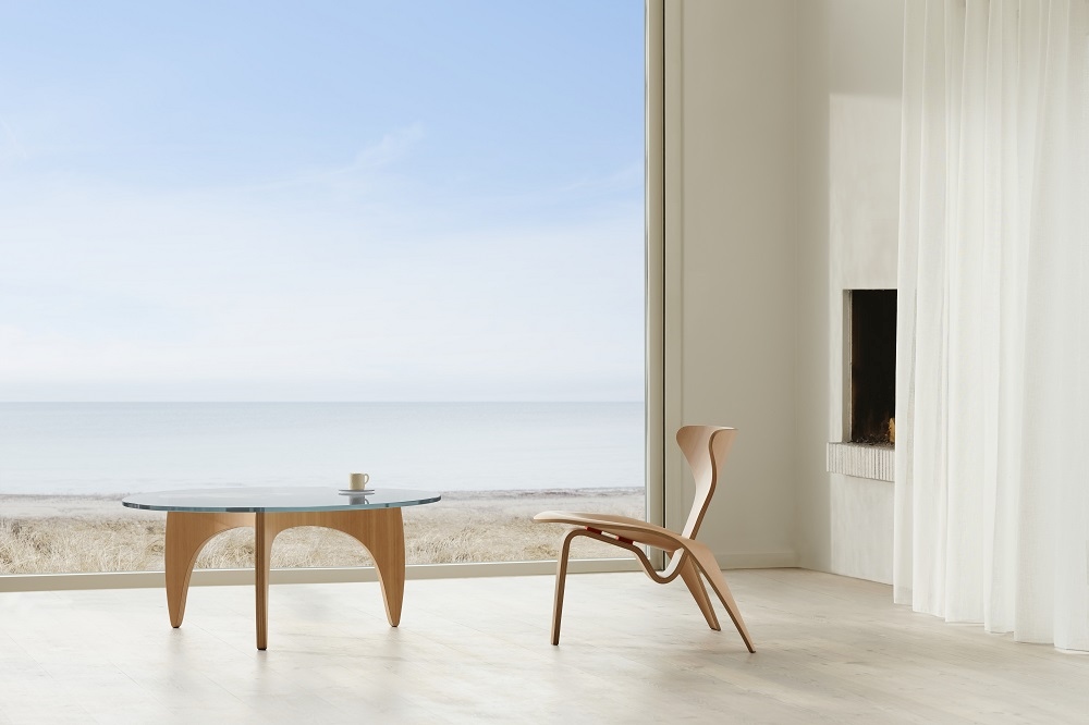 Heller Raum mit PK60 Couchtisch von Fritz Hansen und Holzstuhl vor großem Fenster.