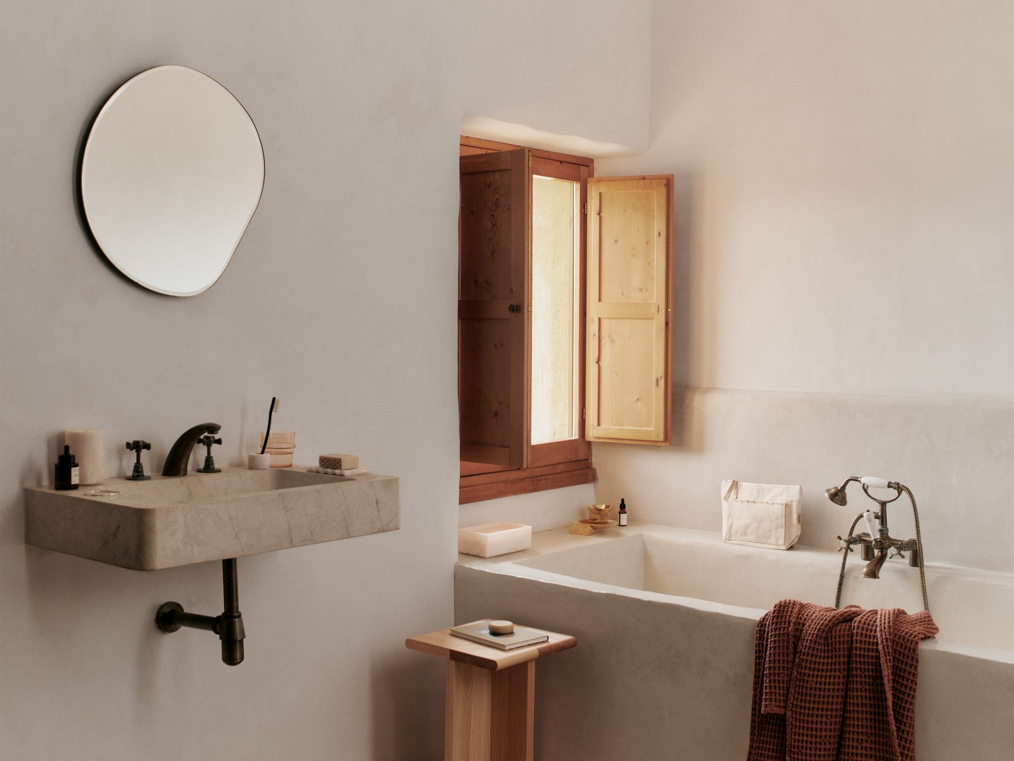 Badezimmer mit Marmorwaschbecken, Badewanne und Sala Piece Beistelltisch von Ferm Living aus hellem Holz.