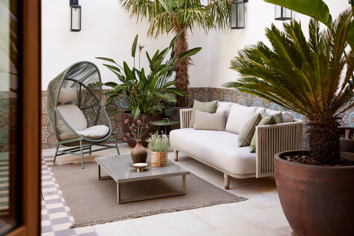 Draufsicht: Cane-Line Hive Sessel, Outdoor-Sitzgruppe mit Sofa, Tisch und Teppich im Garten.