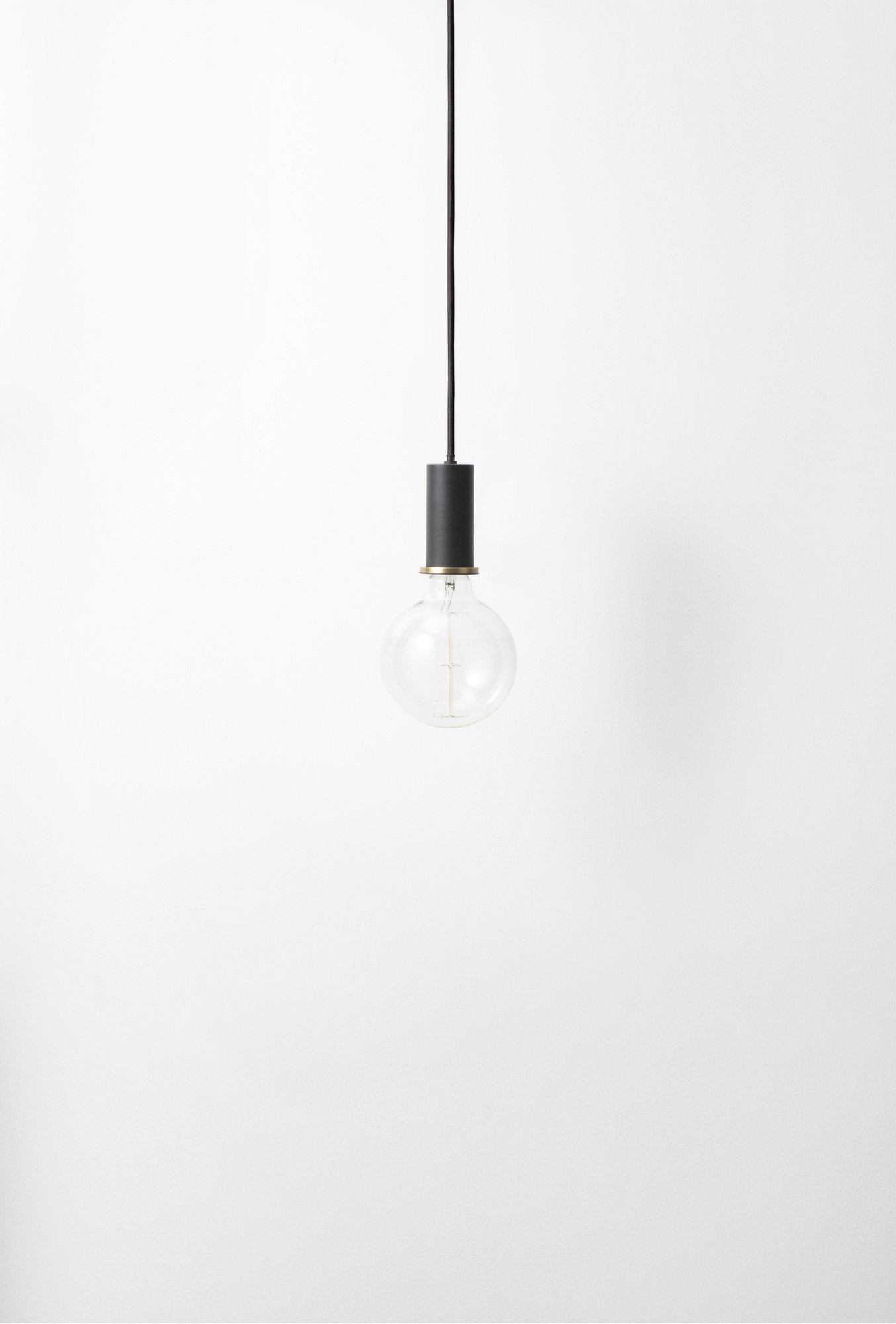 Schwarze Collect Pendelleuchte von Ferm Living mit Glühbirne vor weißem Hintergrund. Hängelampe für Wohnraum.