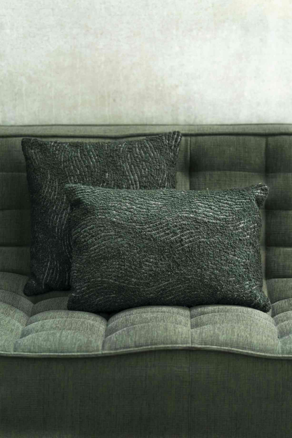 Zwei grüne Ethnicraft Kissen "Wave Cushion Forest" 50x50 cm mit gewebter Textur auf einem Sofa.