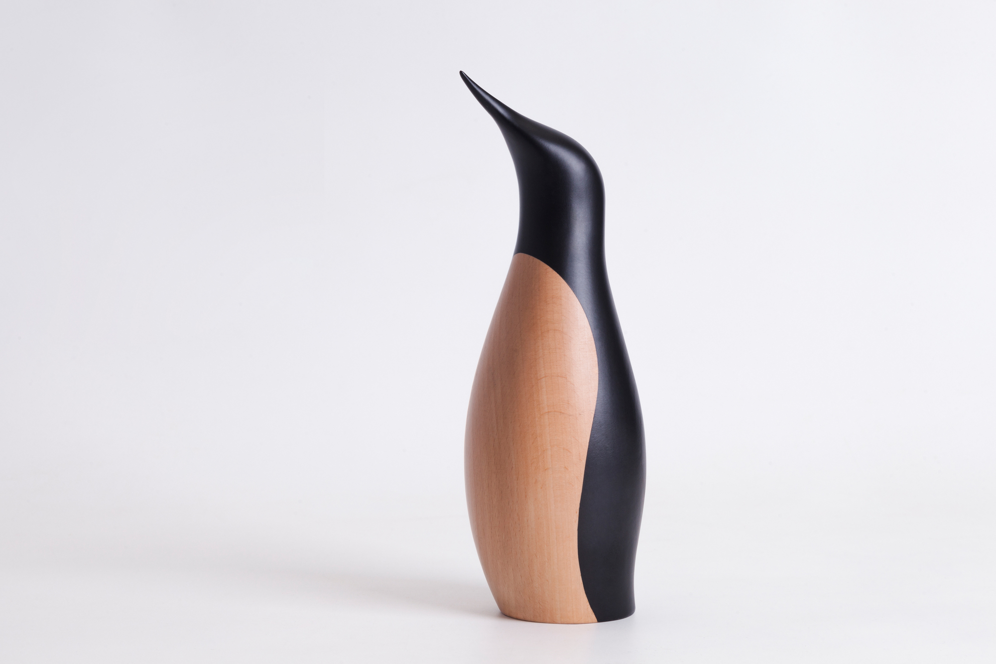Detailaufnahme: Architectmade Pinguin Holzfigur, helles Holz und schwarze Farbe, modernes Design.