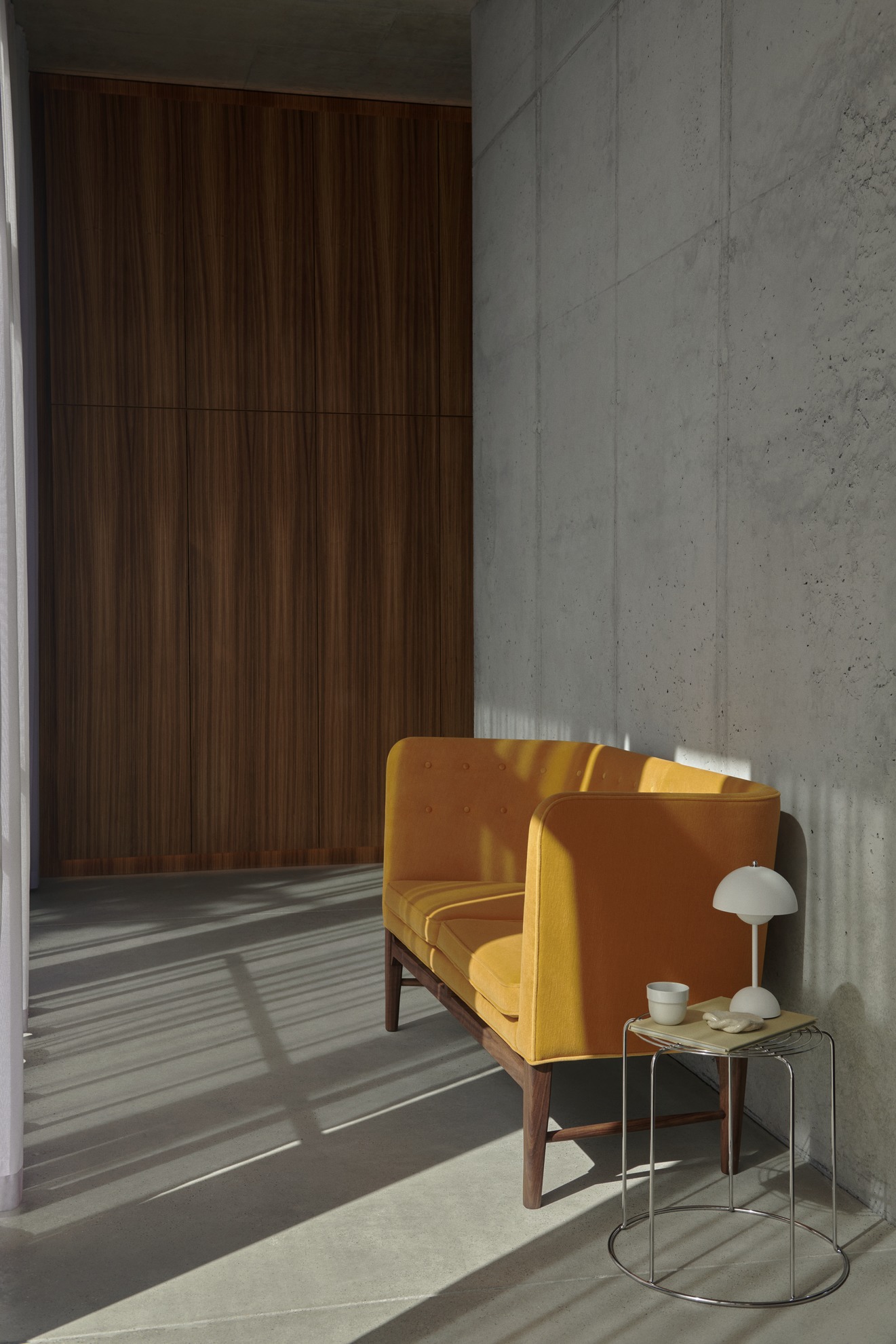 AndTradition Wire Stool VP11 Beistelltisch aus verchromtem Stahl neben einem gelben Sofa in modernem Interieur.