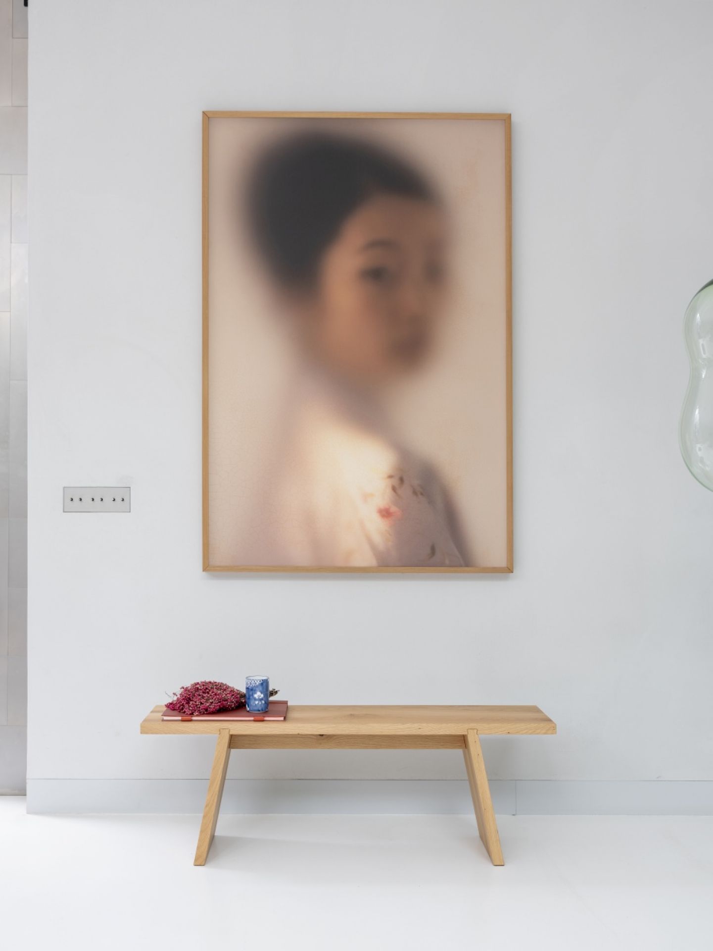 Helles Holzbank mit Dekoration vor einem verschwommenen Porträt, minimalistisches Interieur für Wohnzimmer oder Flur.