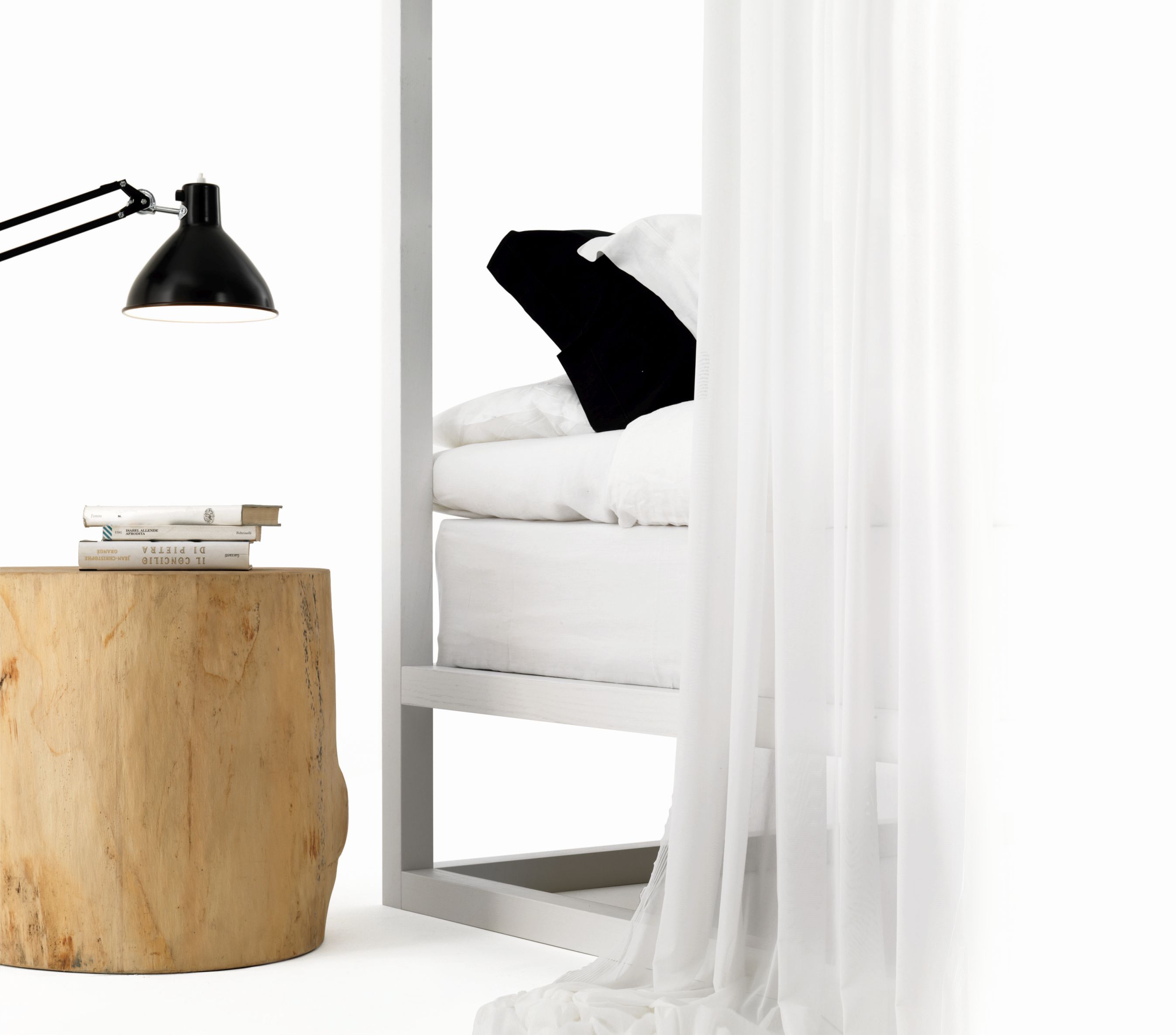 Helles Casetta Himmelbett von Mogg mit Vorhängen, Holztisch und Lampe im Schlafzimmer.