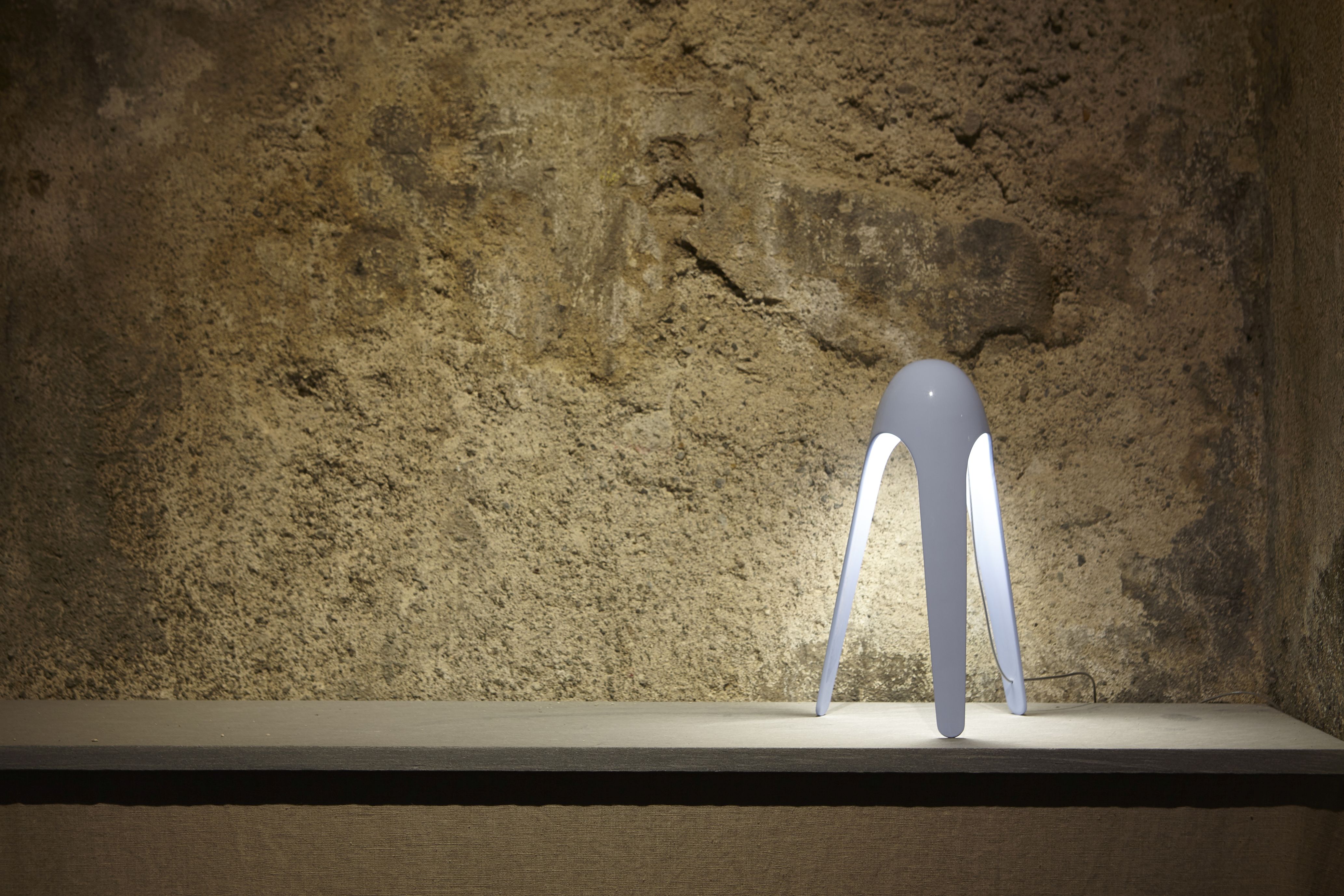 Weiße Cyborg Tischleuchte von Martinelli Luce mit drei Beinen auf einem Regal.