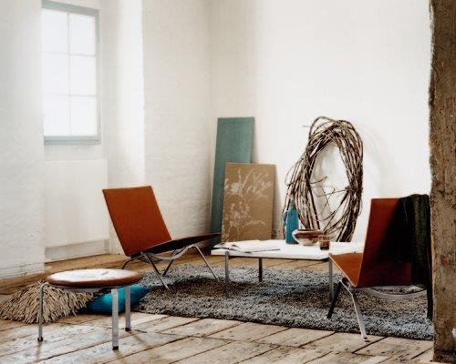 Innenaufnahme mit zwei braunen PK22 Sesseln von Fritz Hansen und einem Beistelltisch auf einem Teppich.